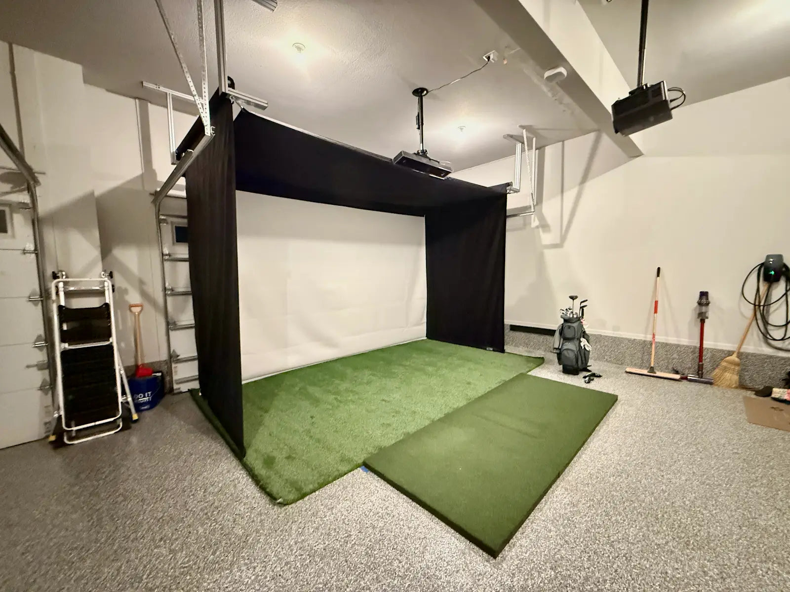 Indoor golf simulator setup in a garage with Retractable Golf Simulator Enclosure