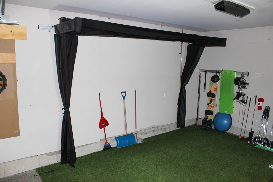 Indoor golf practice area with artificial grass, golf clubs, and sports equipment. SportScreen Vanish Lite Retractable Golf Simulator enclosure.